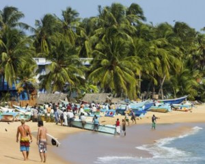 Tourists stroll whilst local fishermen work on this popular surf beach, Arugam Bay, Eastern Province, Sri Lanka, Asia